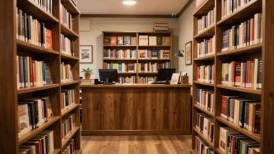 Interior aconchegante de uma livraria virtual em um jogo de simulação, com estantes repletas de livros, balcão de atendimento e decoração acolhedora
